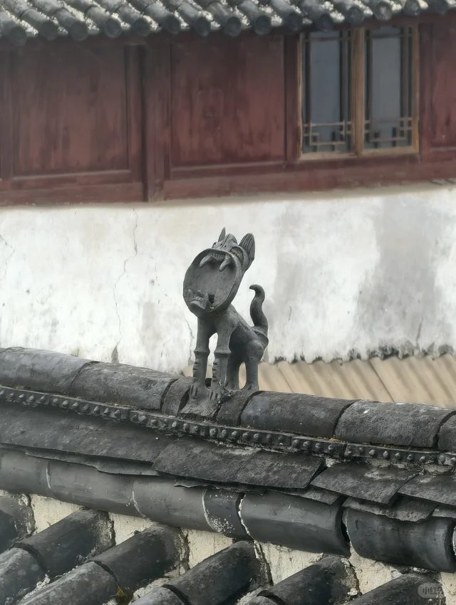 A tile cat on an old grey-tiled roof