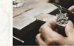 Silversmith chasing a pendant on the bench